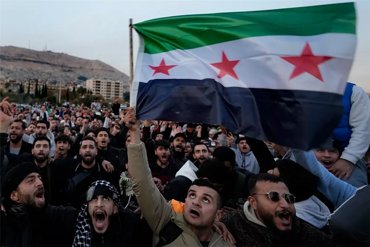 أحد السوريين يرفع علم الثورة السورية عقب سقوط نظام الأسد
