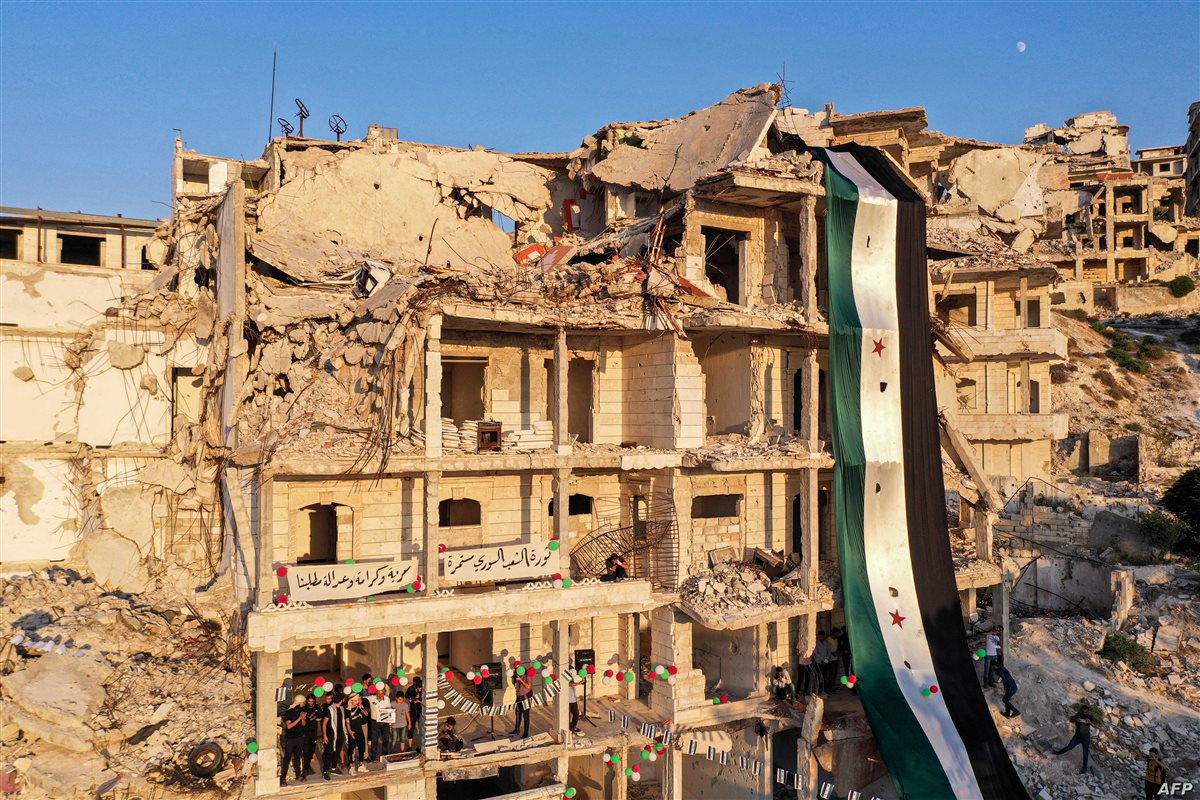 <strong>علم الثورة السورية على أحد المنازل المدمرة (الحرة)</strong>