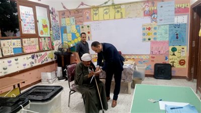 رئيس لجنة انتخابية يساعد مسنًا للإدلاء بصوته في سوهاج